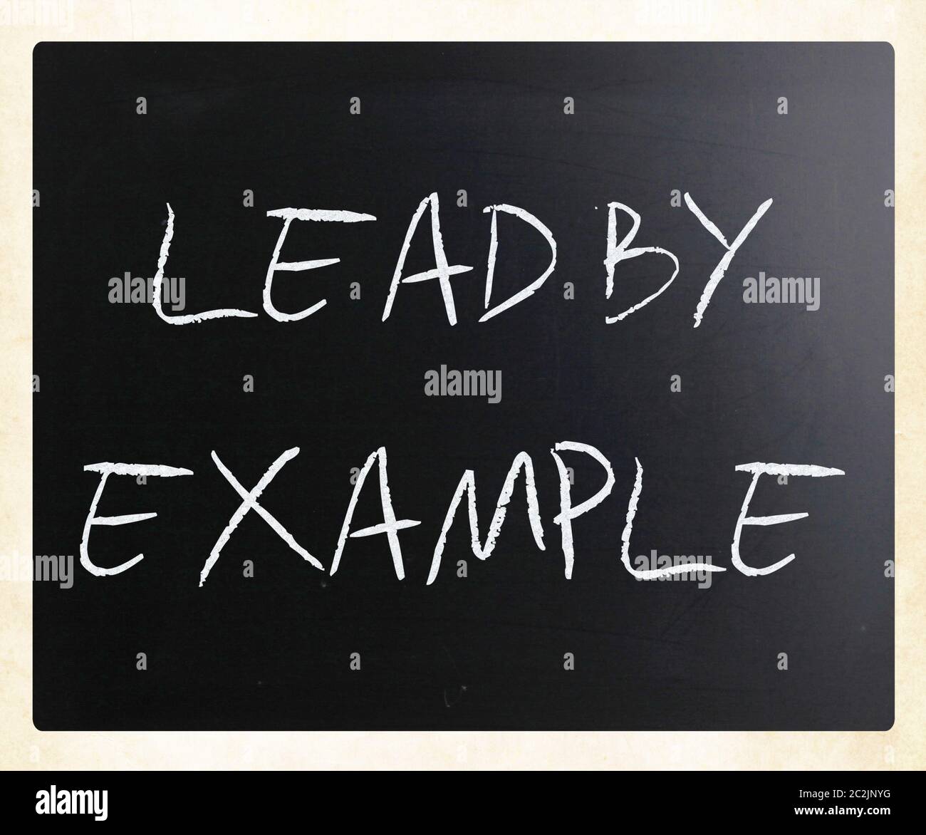 "Lead by example" handwritten with white chalk on a blackboard. Stock Photo