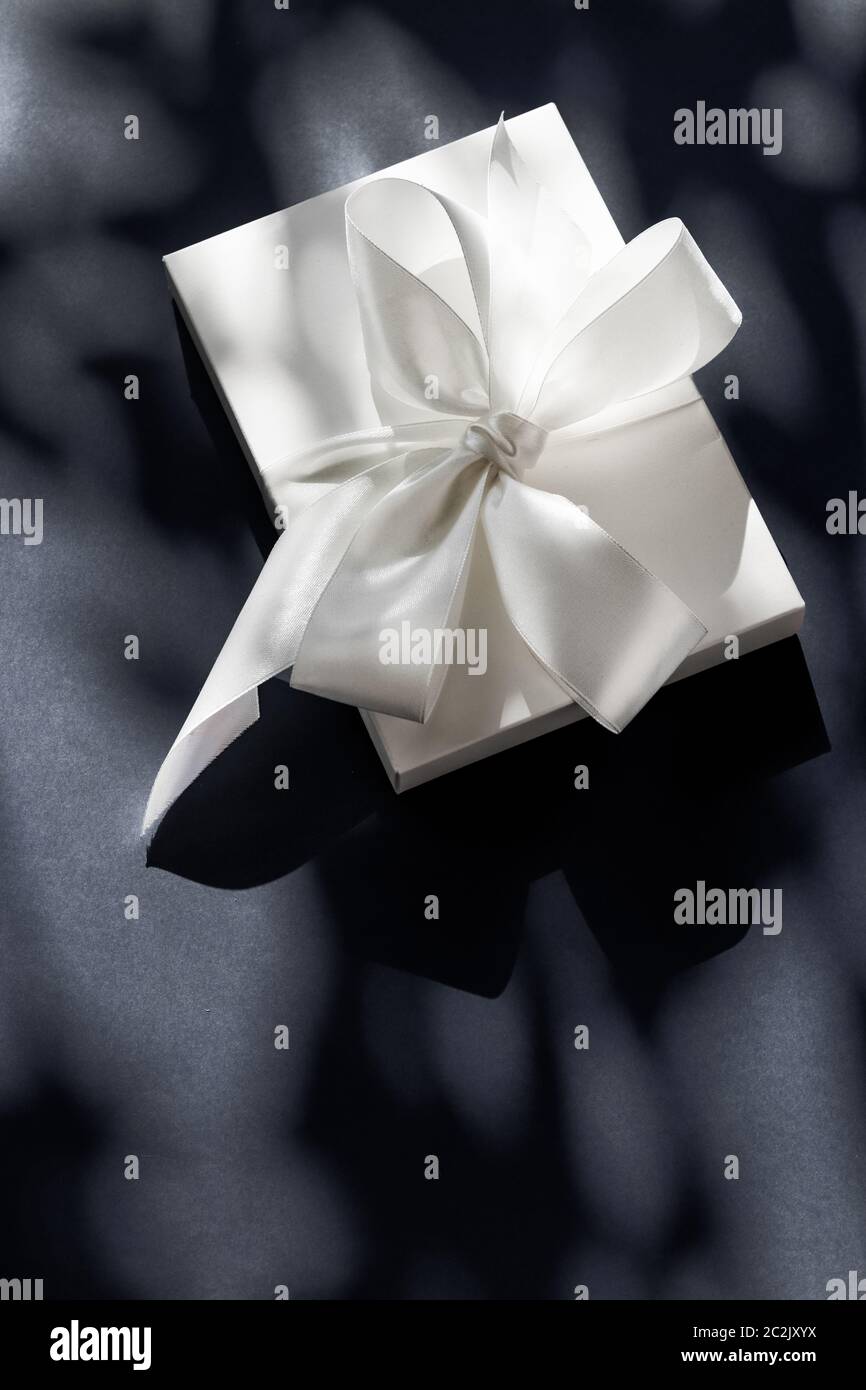 Luxury holiday white gift box with silk ribbon and bow on black ...