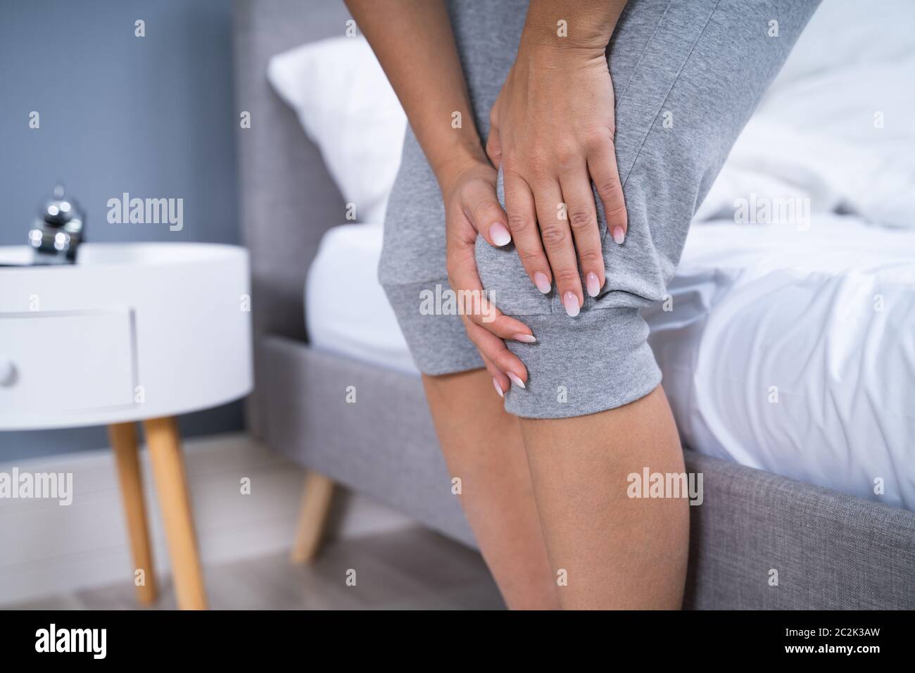 Woman Suffering From Knee Pain Sitting In Bed Stock Photo Alamy