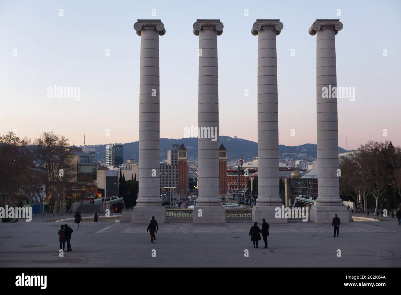 The Four Columns (Les Quatre Columnes) in Avinguda Maria Cristina in Montjuïc in Barcelona, Catalonia, Spain. The Four Columns designed by Catalan modernist architect Josep Puig i Cadafalch were erected in 1919, demolished in 1928 and erected again by Spanish sculptor Andreu Alfaro in 1999. The Venetian Towers (Torres Venecianes) on Plaça d'Espanya are seen in the background. Stock Photo