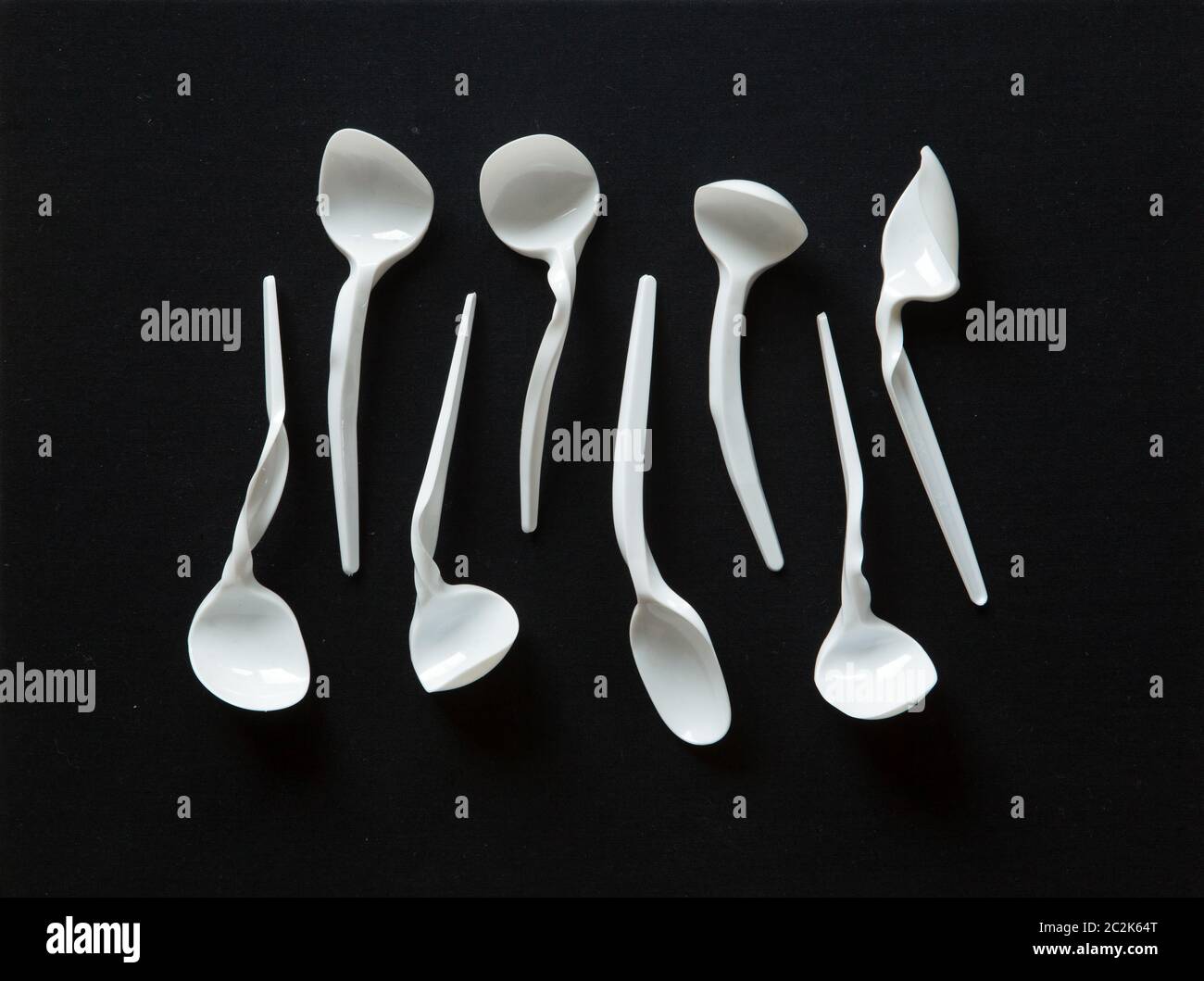 Plastic disposable spoons heavily deformed in hot water. Stock Photo