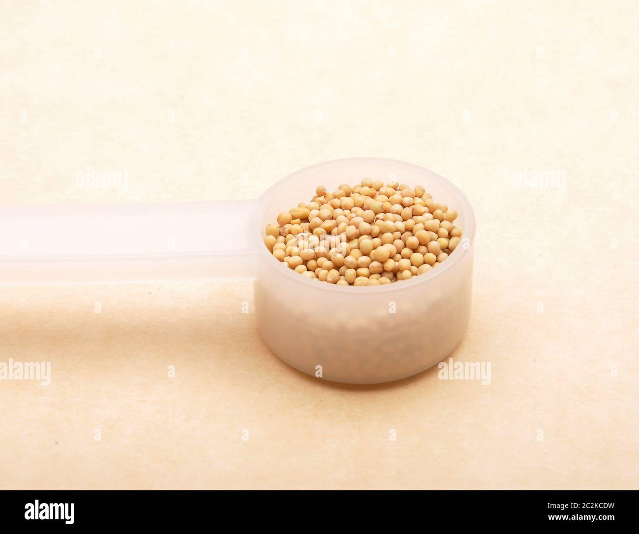 Mustard seeds in measuring spoon on brown background Stock Photo