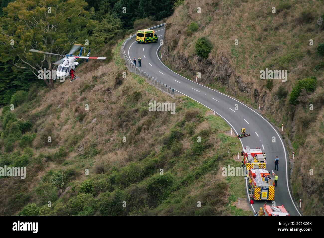 A rescue helicopter hovers over the scene of a motor vehicle accident on a hillside in Banks Peninsula, New Zealand Stock Photo