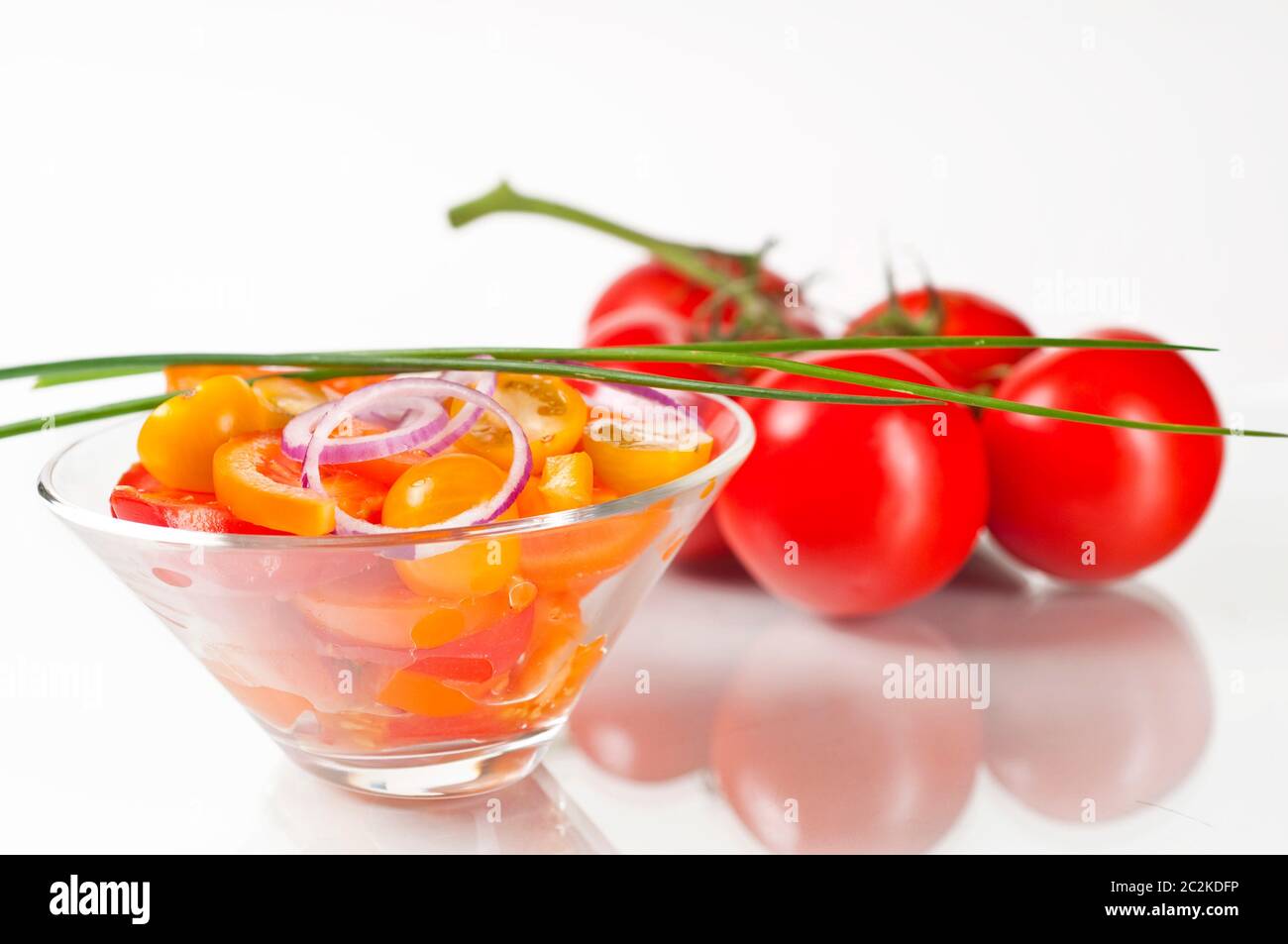 Tomatensalat in Glasschale auf weißem Hintergrund mit Spiegelung Stock Photo