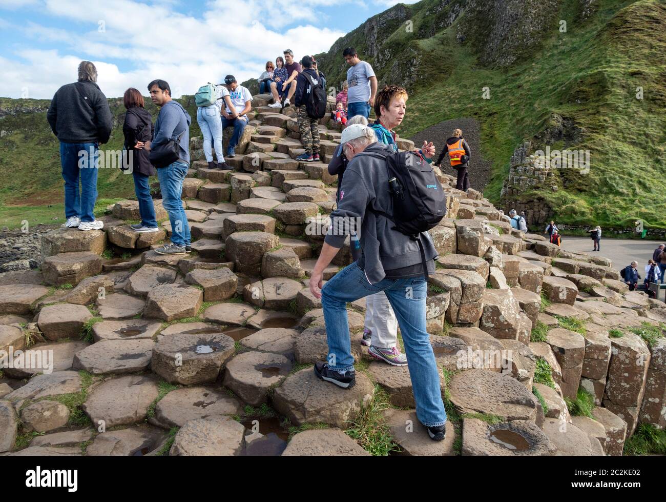 Tourists walking over geometrical basalt columns rock formations at Giant's Causeway, Northern Ireland, Europe Stock Photo