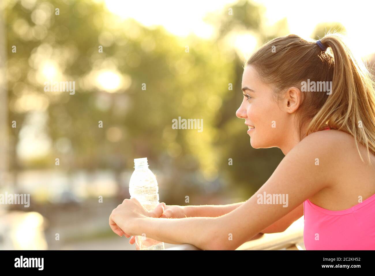 Happy runner resting holding a water bottle looking away in a balcony ...