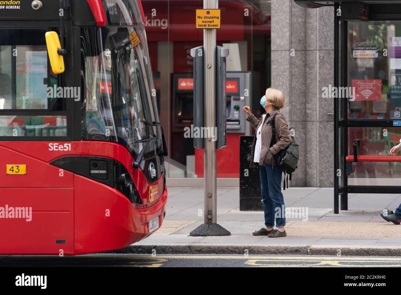 Passenger wearing a face mask at a London Transport bus stop on