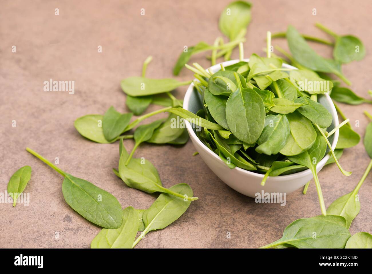 Fresh green spinach leaves on a brown textured background Stock Photo
