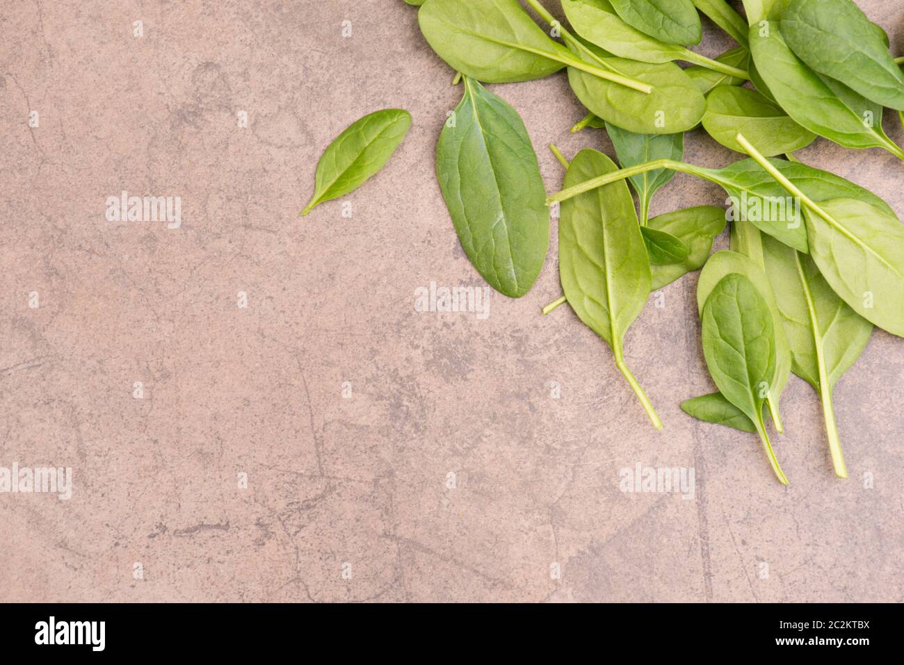 Fresh green spinach leaves on a brown textured background Stock Photo