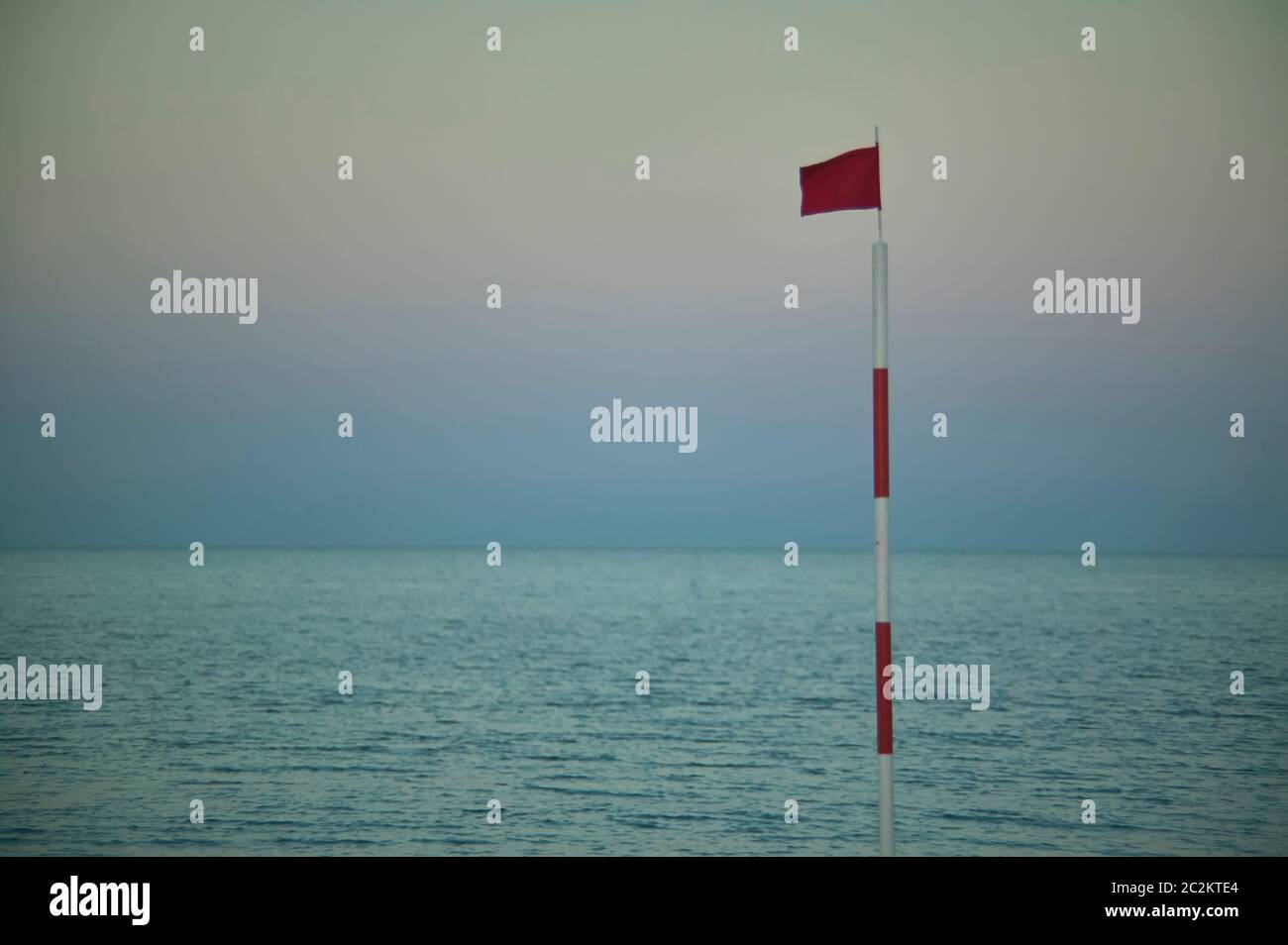 Pole with raised red flag, symbol of danger for bathers and navigators ...