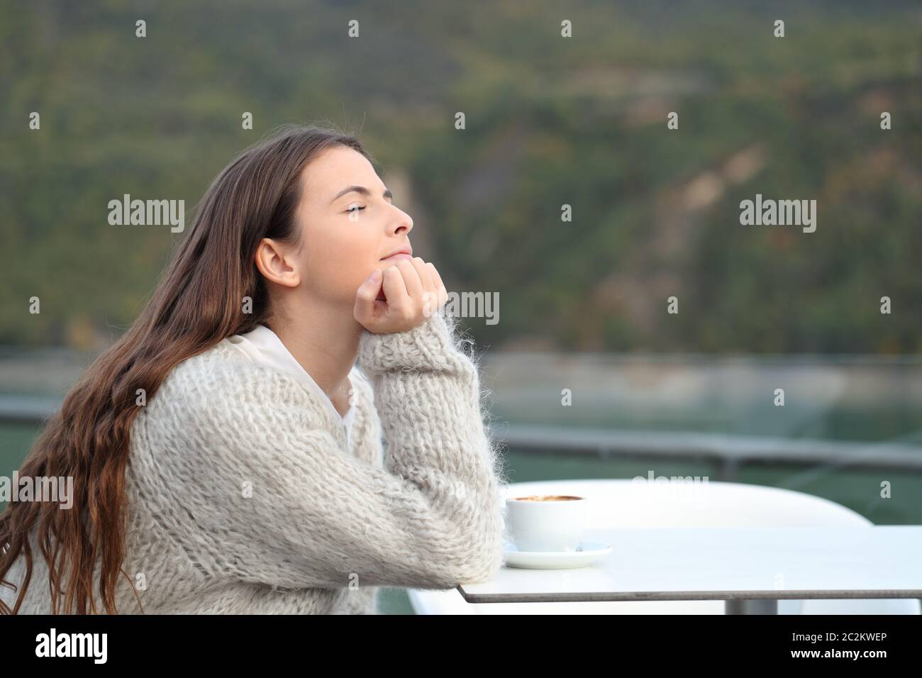Relaxed girl meditating sitting in a coffee shop terrace in a mountain ...