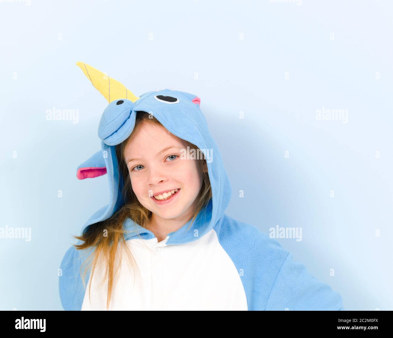 pretty blonde girl with cozy blue unicorn costume is posing in the studio in front of blue wall Stock Photo