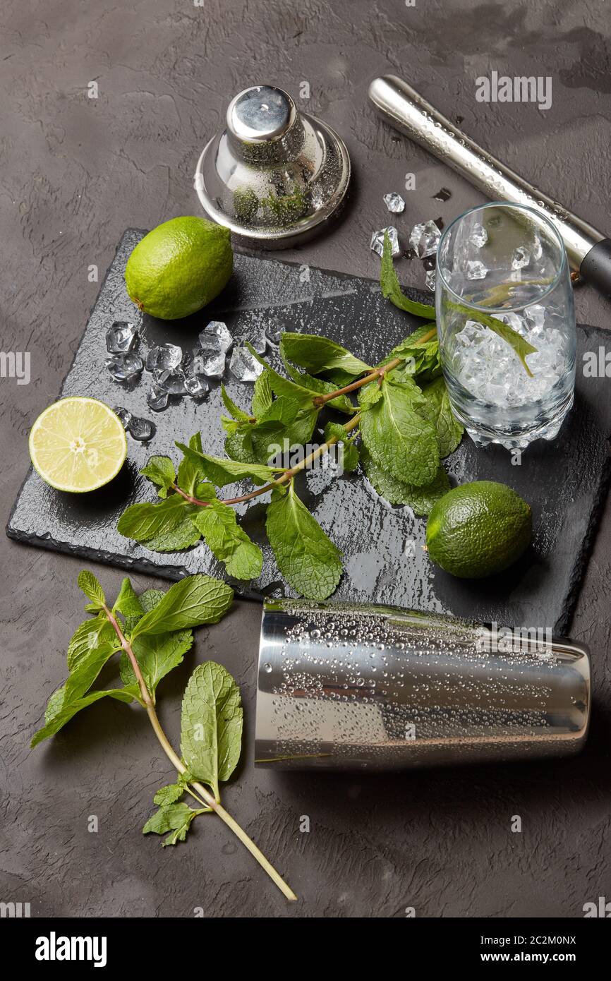 Set of bar tools: cocktail shaker, muddler and glass with ice, lime and  mint on dark stone table. Top view. Bartender's tool. Mojito cocktail  making Stock Photo - Alamy