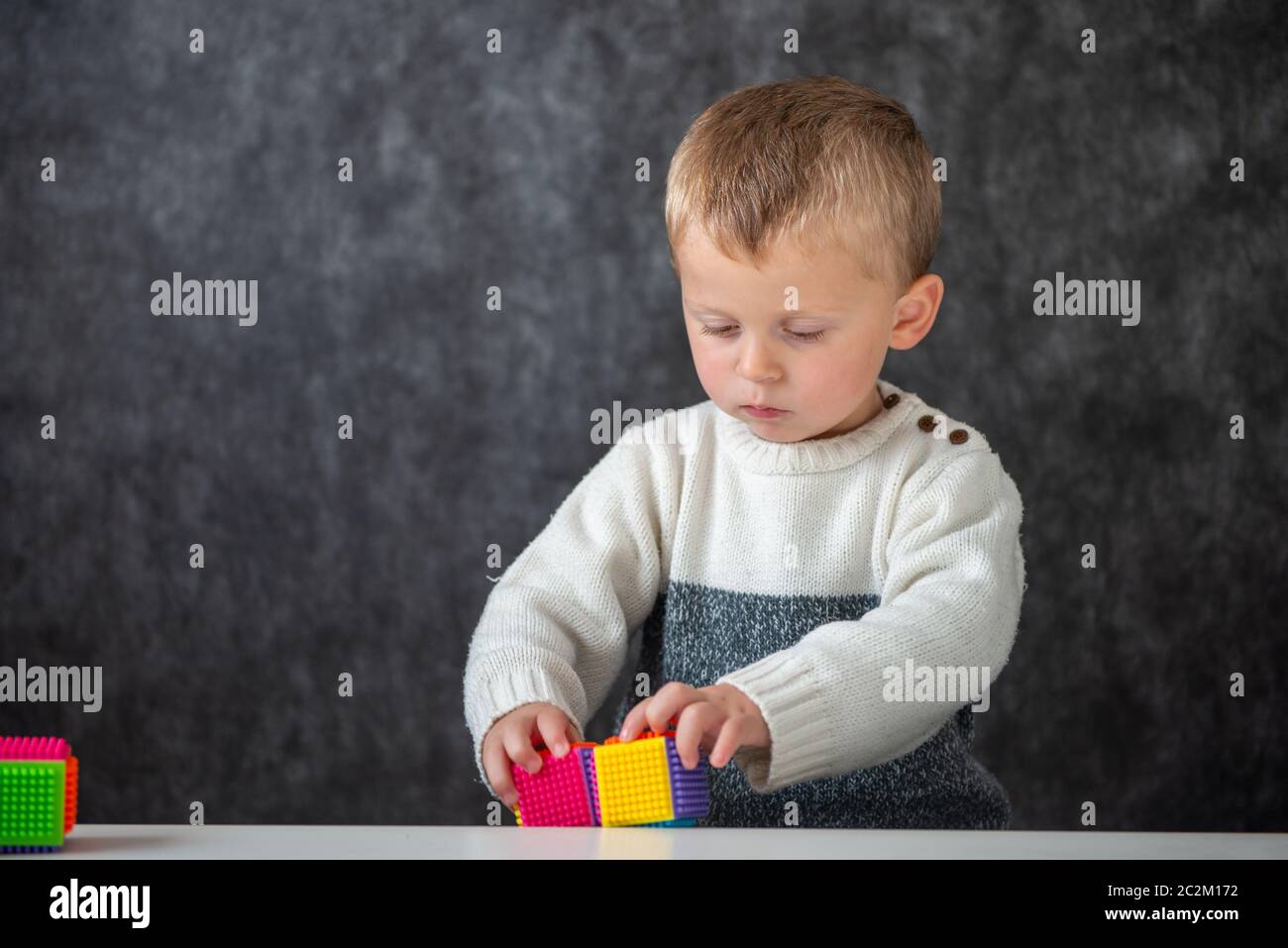 a two years old baby playing with cubes Stock Photo