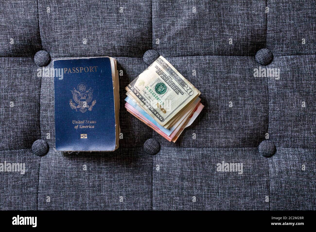 Old well-used US passport next to US and international currency Stock Photo