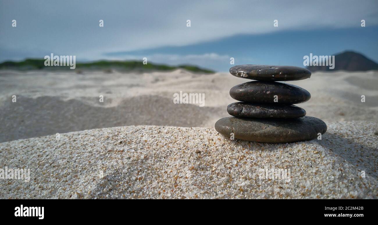 Stack of pebbles on the beach sand: Zen evocative image of inner peace, tranquility and general satisfaction. Stock Photo
