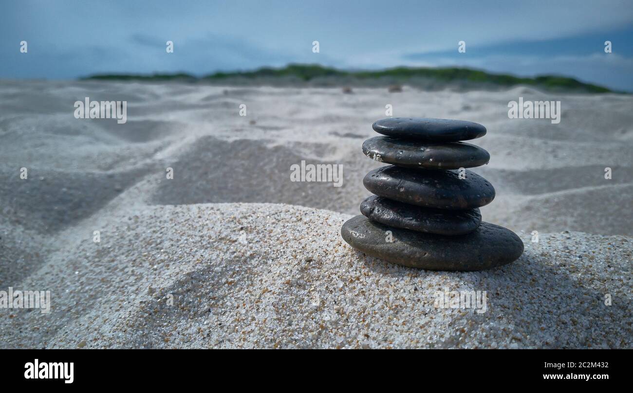 Stack of pebbles on the beach sand: Zen evocative image of inner peace, tranquility and general satisfaction. Stock Photo