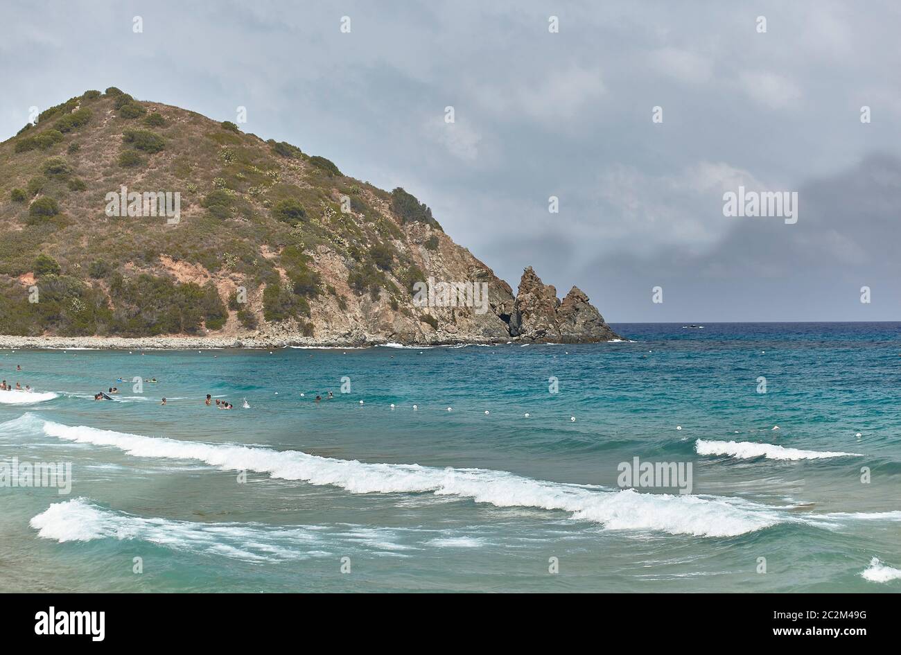 Detail of Mount Turnu in Sardinia: a small natural mountain overlooking the sea with some tourists taking a bath. Stock Photo