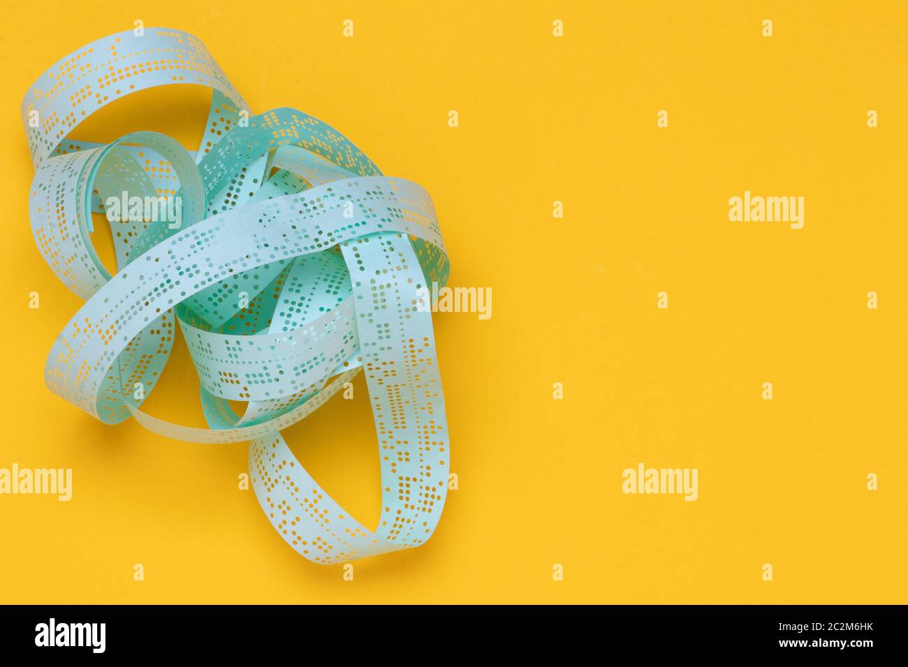 Storage media. Closeup of a vintage old perforated punched tape with old data on a yellow