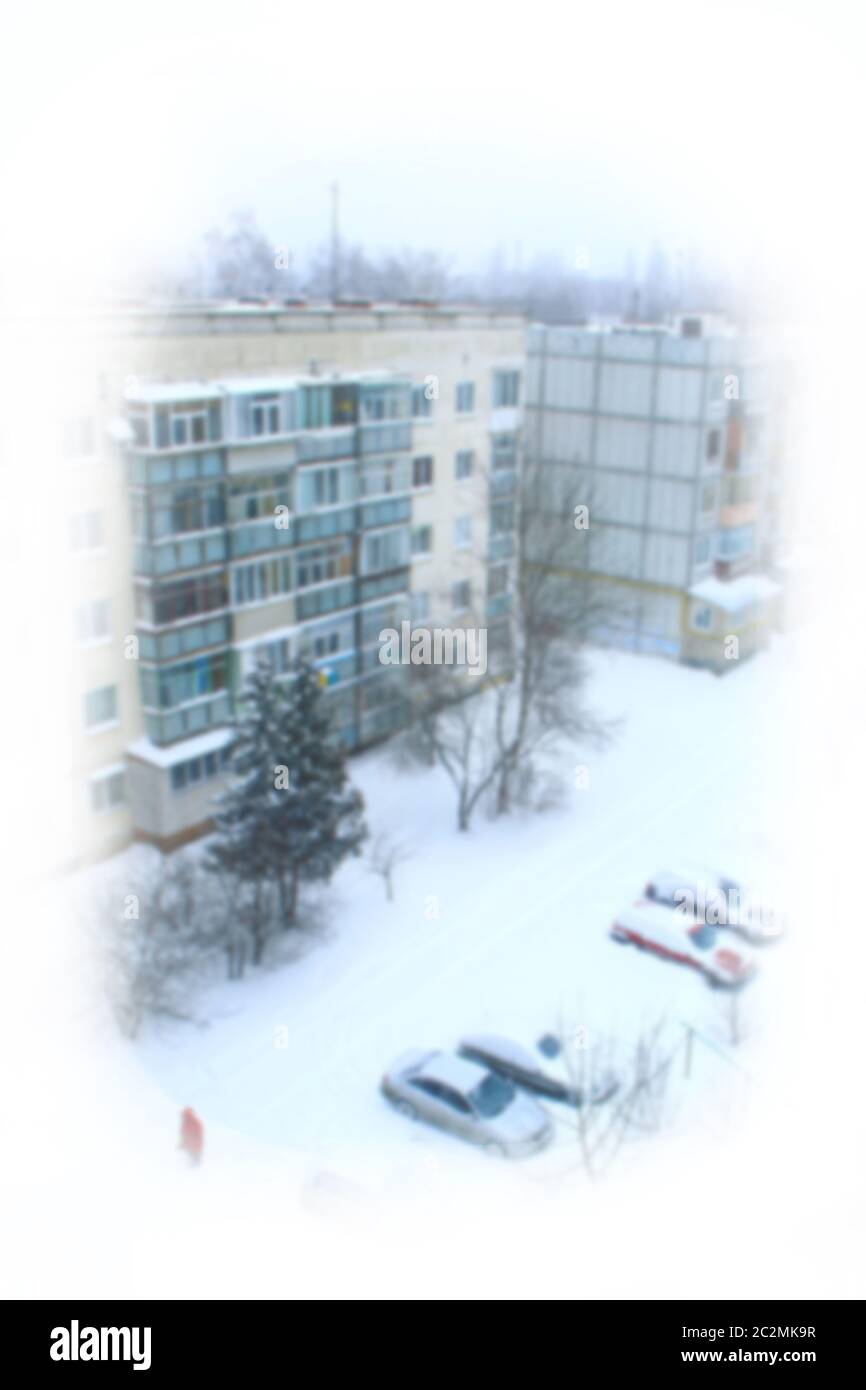 View from frozen window on snowy winter in town yard. Cars parked in winter city. Bad winter weather Stock Photo