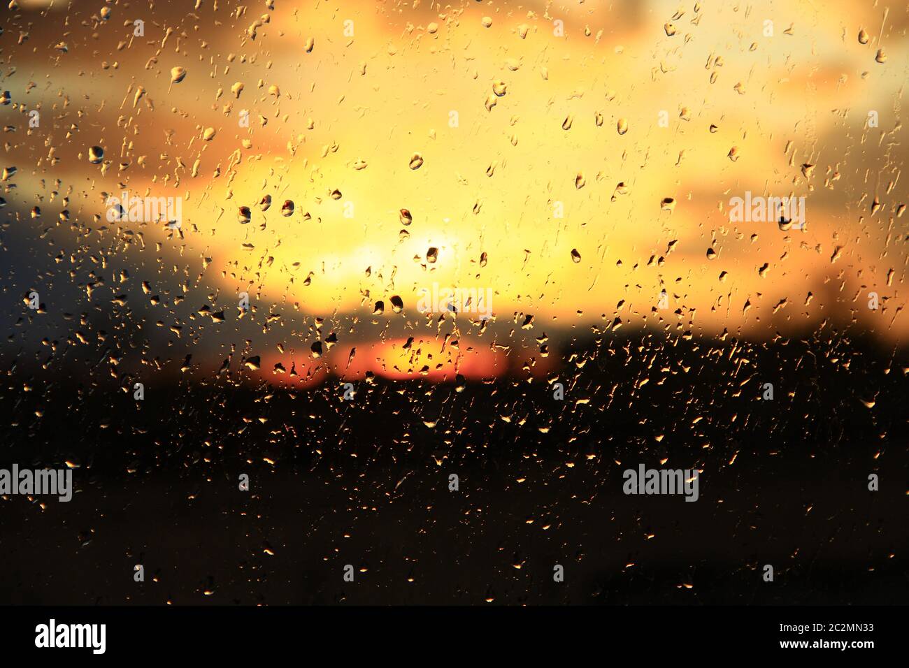 Rain outdoor window on background of sunset. Rain drops on glass during rain. Sunset outside