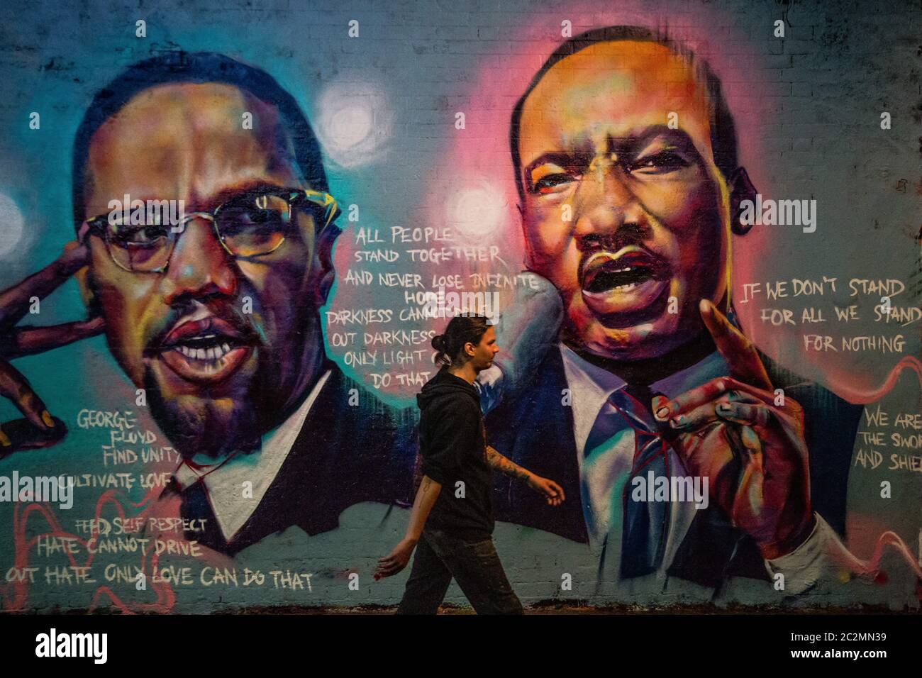 London, UK. 17th June, 2020. A man walks past a mural of Malcom X and  Martin Luther King paying tribute to George Floyd, a Black man who died in  police custody in