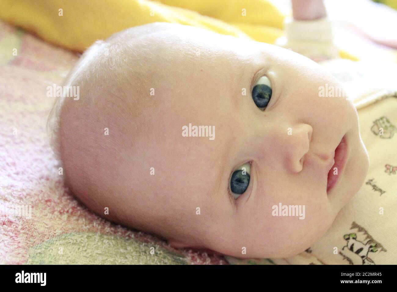 Portrait of smiling baby with blue eyes. Newborn child looking at mother Stock Photo