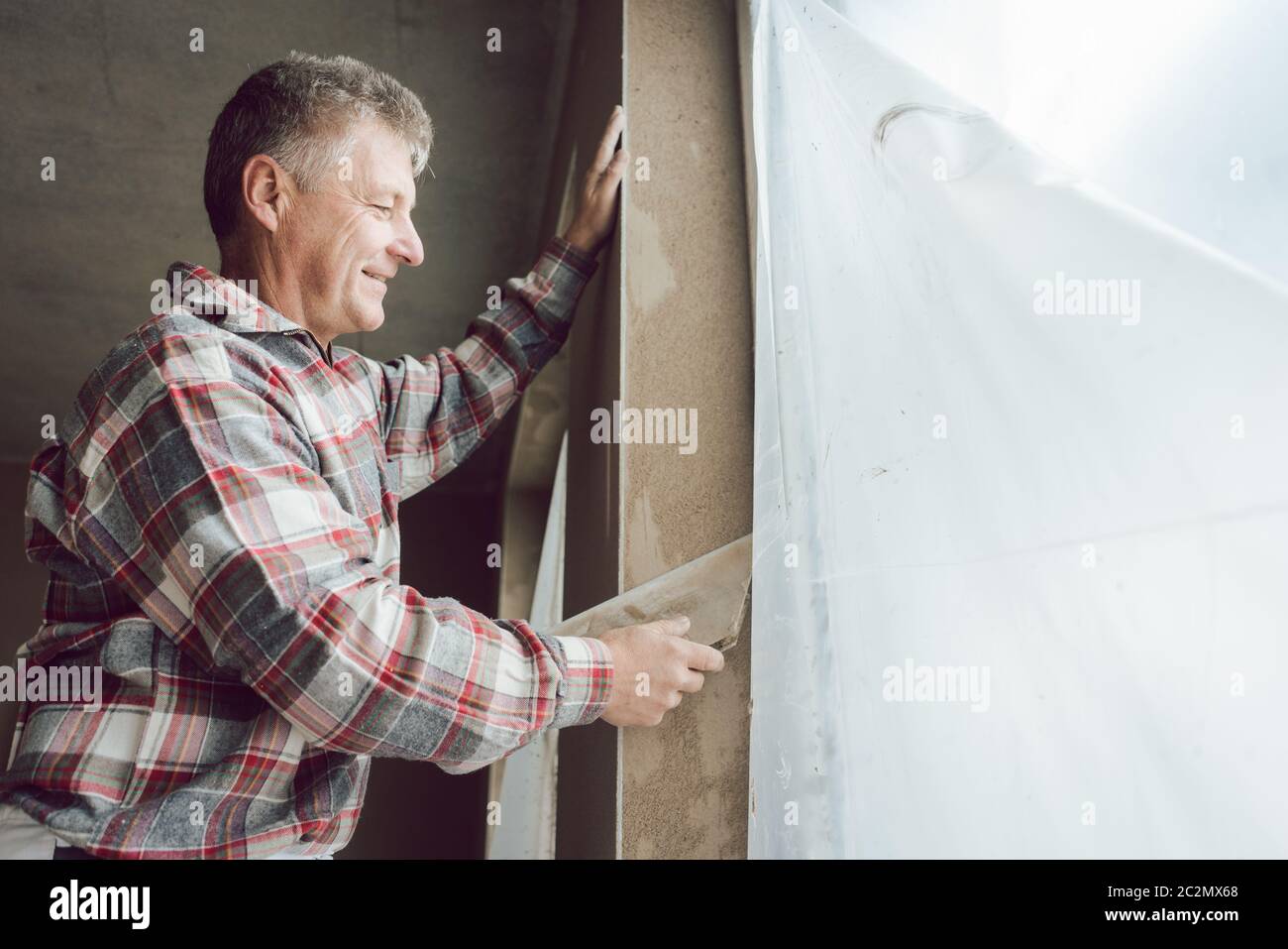 Diligent plasterer working on a window opening Stock Photo
