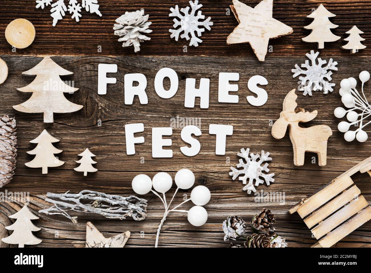 White Letters Building The Word Frohes Fest Means Merry Christmas. Wooden Christmas Decoration Like Sled And Tree And Star. Brown Wooden Background Stock Photo