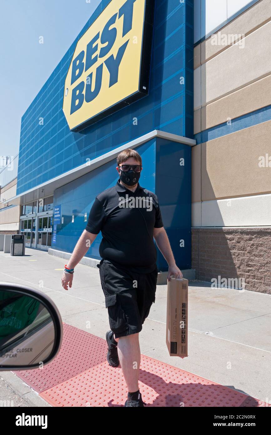Masked Best Buy employee delivering boxed TV to car practicing social distancing due to the Covid-19 pandemic. Maplewood Minnesota MN USA Stock Photo