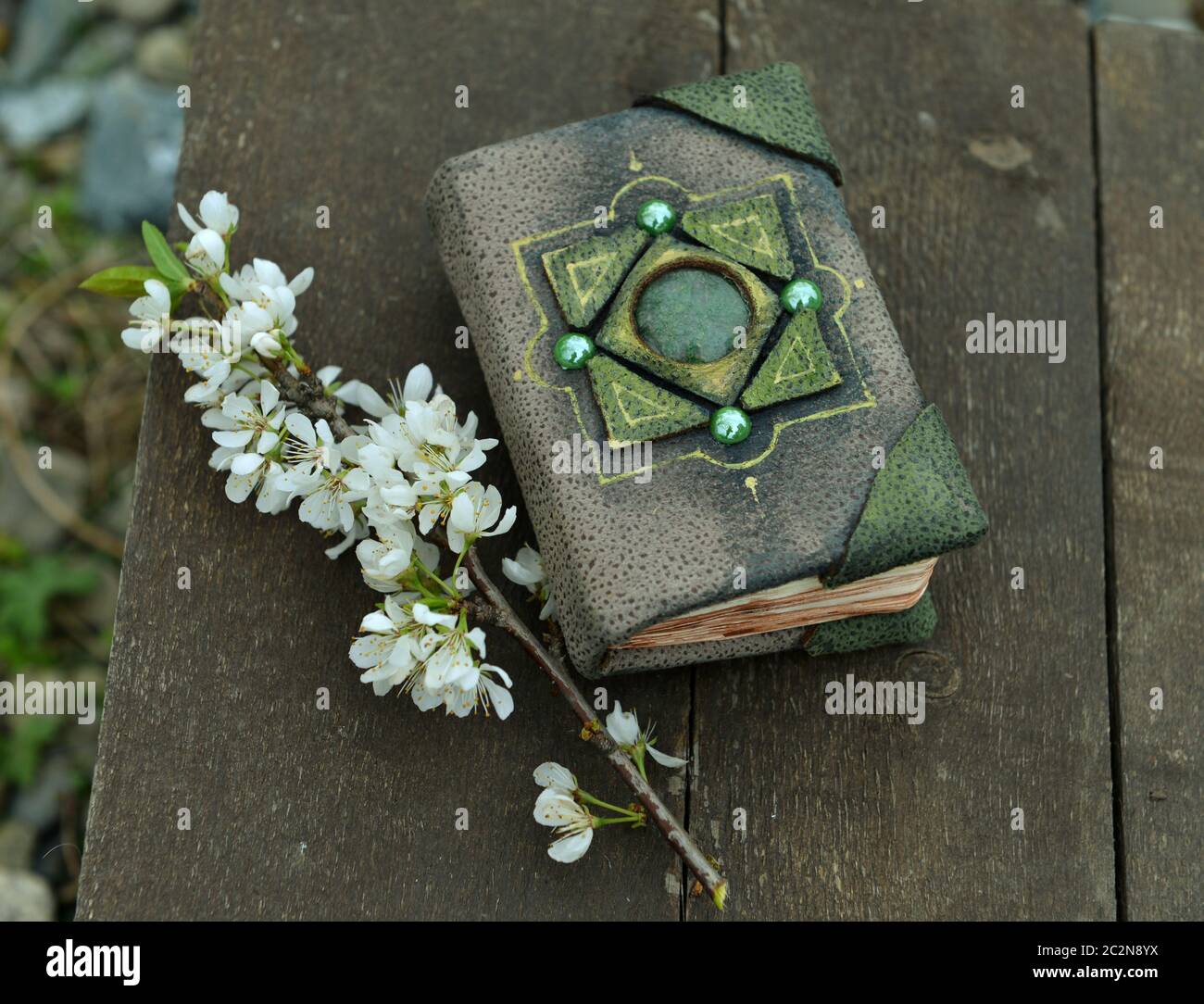 Hand crafted diary book and blooming tree branch on planks. Esoteric, gothic and occult background with magic objects, mystic and fairy tale concept Stock Photo