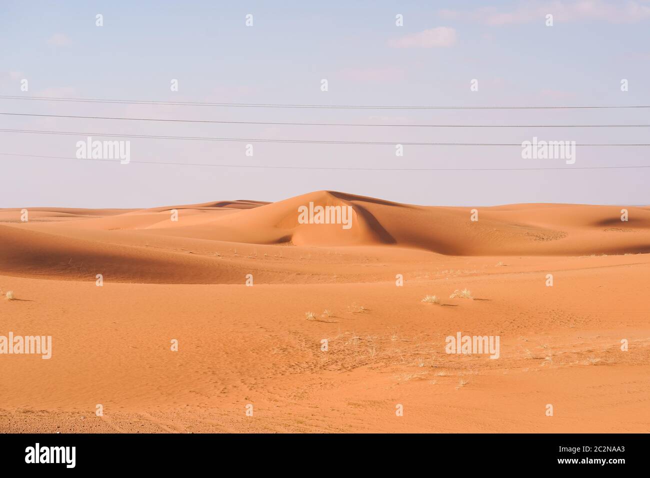 gorgeous desert of reddish sand dunes with power lines and utility ...