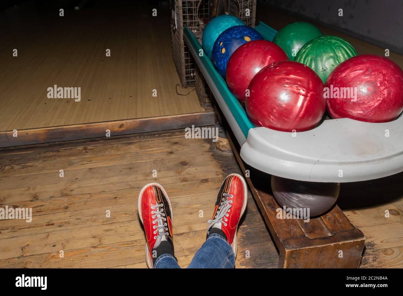 Very old colorful and damaged bowling balls and bowling shoes on man legs background Stock Photo