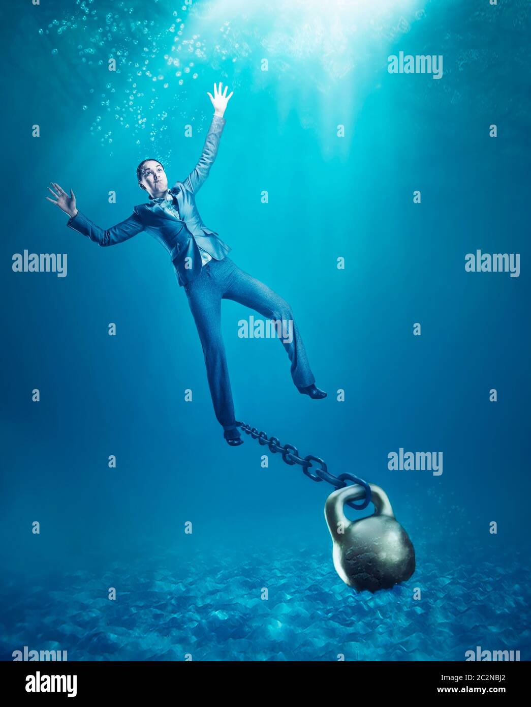 Businesswoman with dumb-bell on her hand sinking in the sea Stock Photo