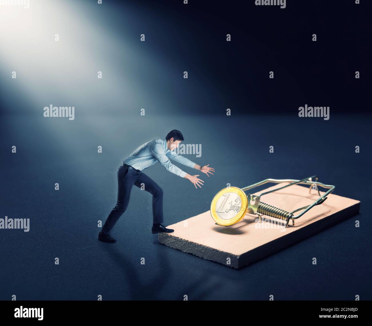 Young businessman trying to pick a gold coin in the mousetrap Stock