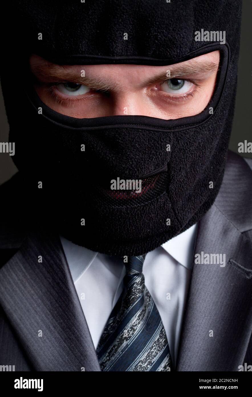 Business crime. Businessman in black balaclava looking to you Stock