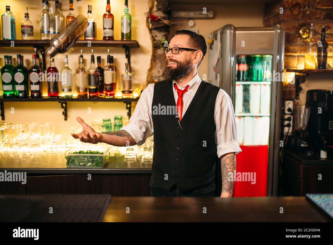 Bartender with shaker show trick behind a bar counter. Modern club