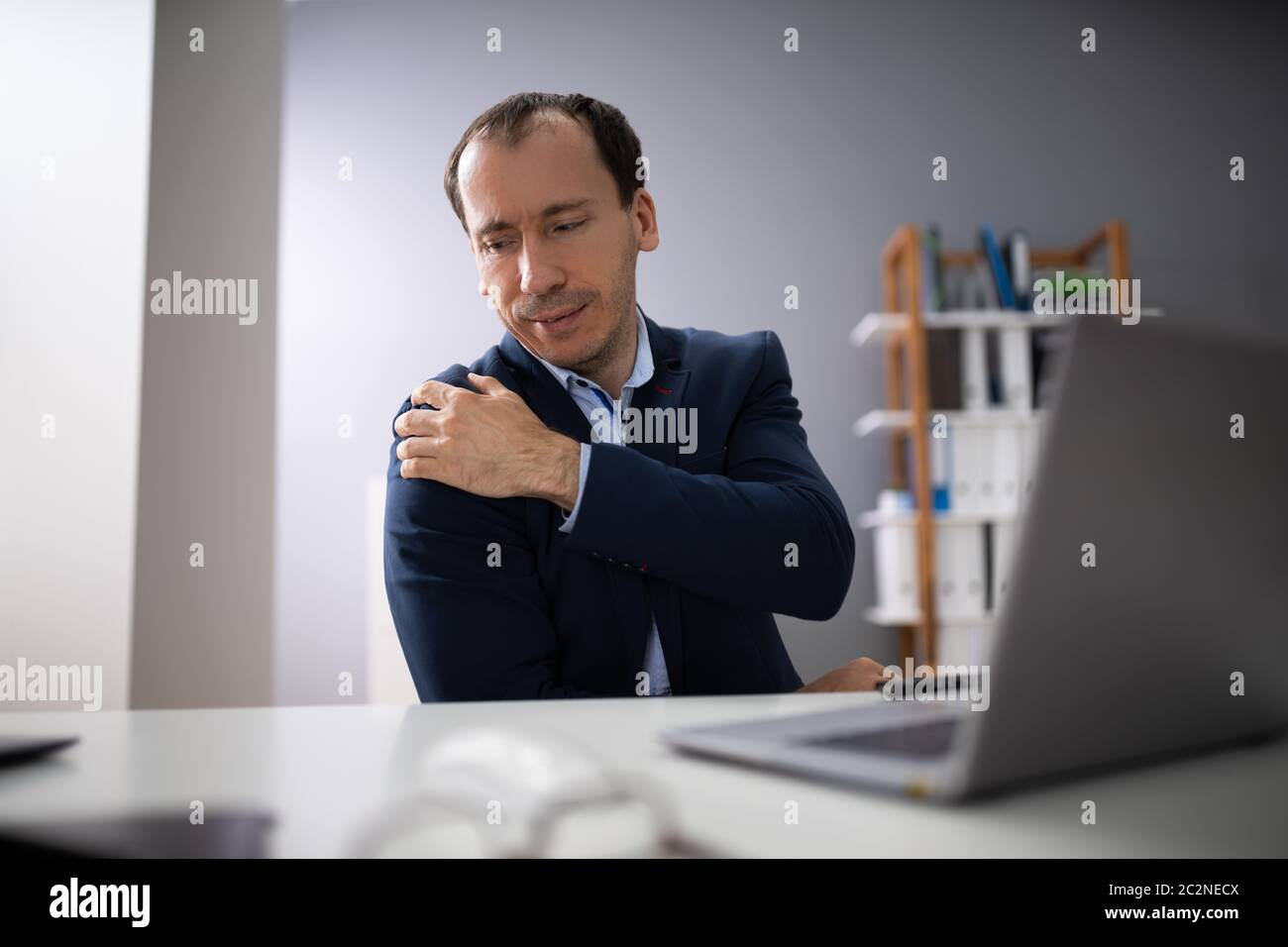 Young Businessman Using Computer Suffering From Shoulder Ache Stock Photo