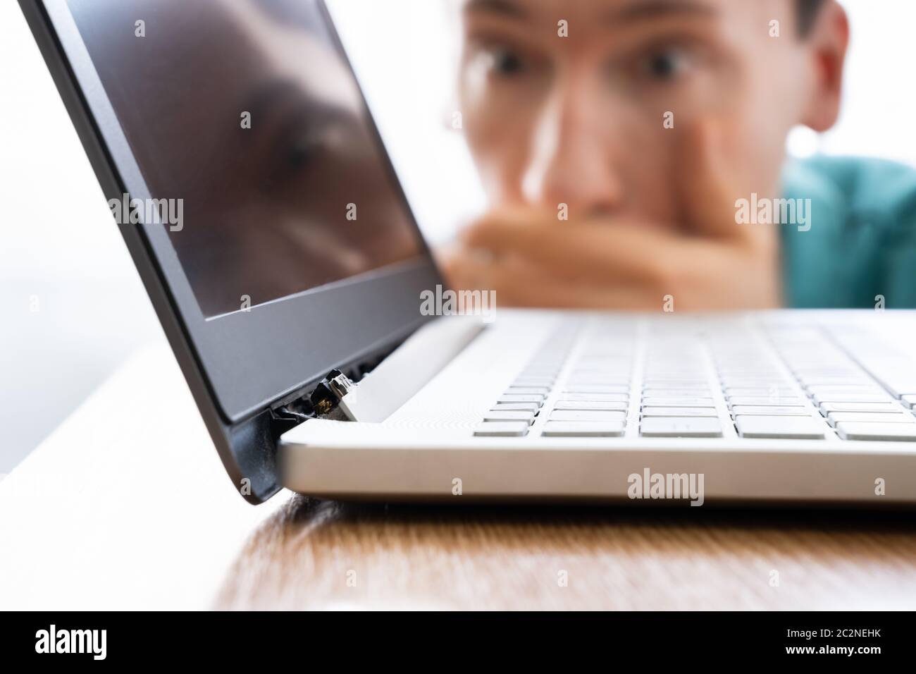 Man Looking At Damaged Laptop Computer With Broken Screen Attachment Stock Photo
