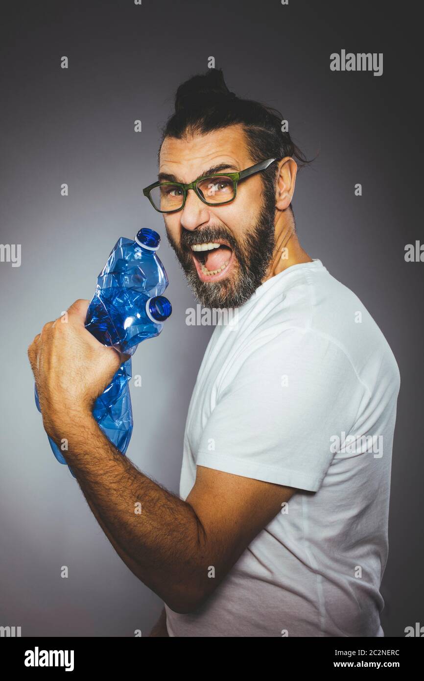 man with beard and glasses is holding plastic bottles. Concept of recycling and excessive use of plastics. Stock Photo