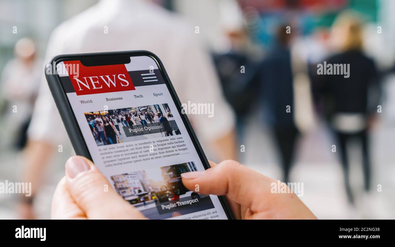 Online news on a mobile phone. Close up of businesswoman reading news or articles in a smartphone screen application. Hand holding smart device. Mockup website. Newspaper and portal on internet. Stock Photo