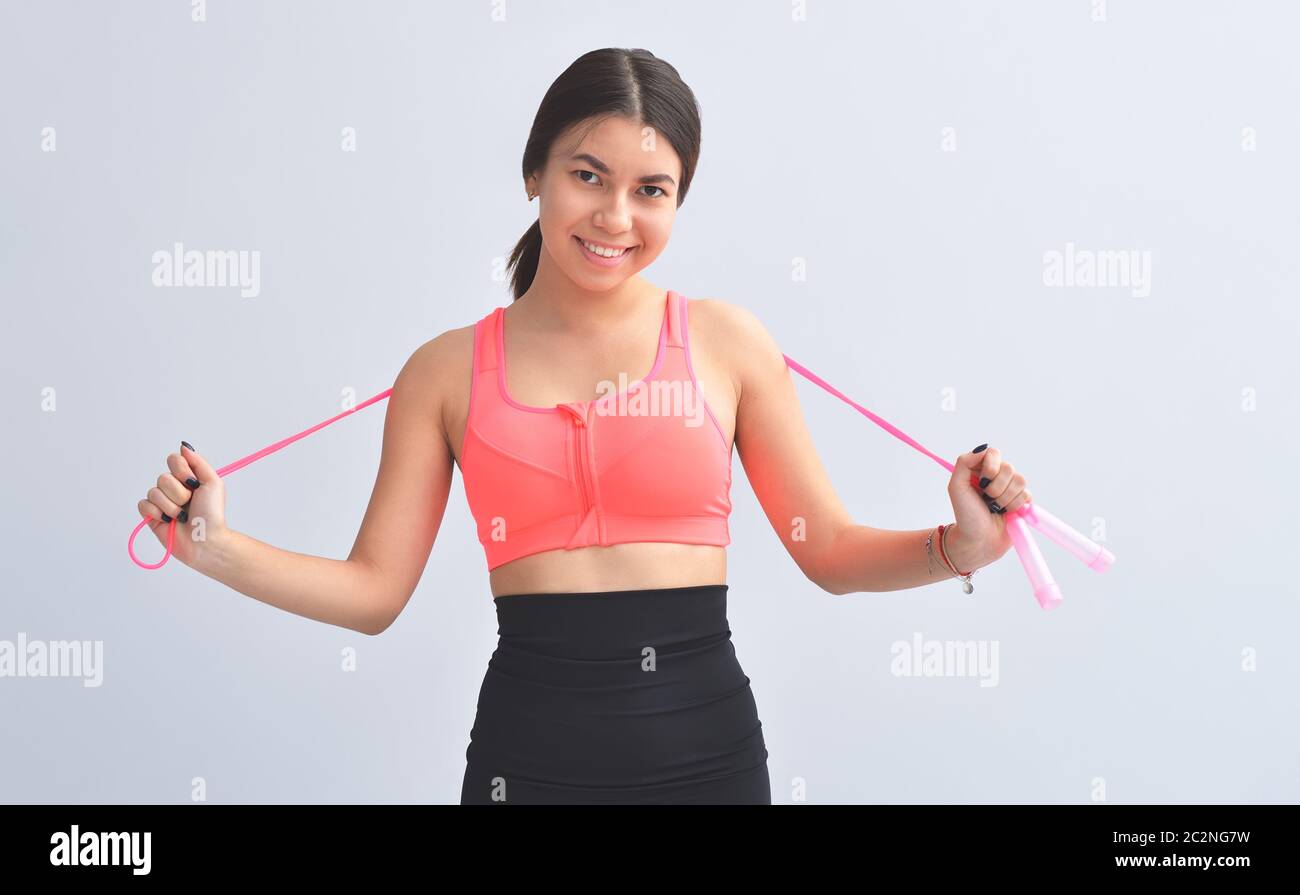 Girl Standing With Rope Young asian girl is standing next to gray background is smiling and ...