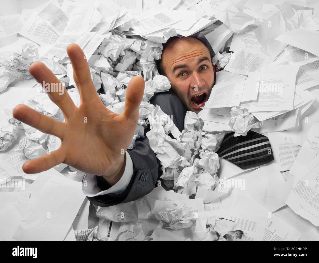 Businessman sinking in heap of documents and asking for help Stock Photo