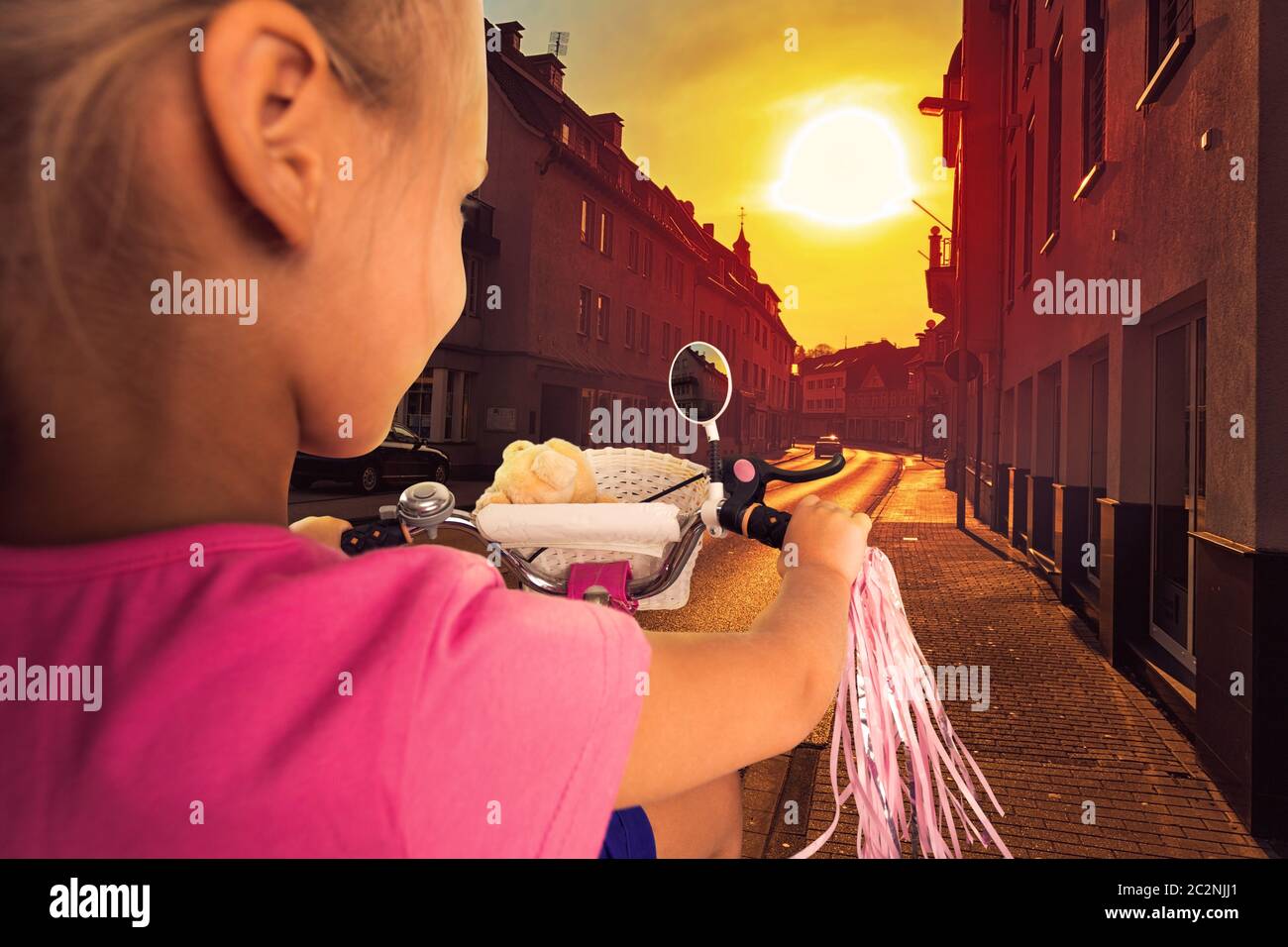 Smiling little girl is cycling on the street in the night Stock Photo