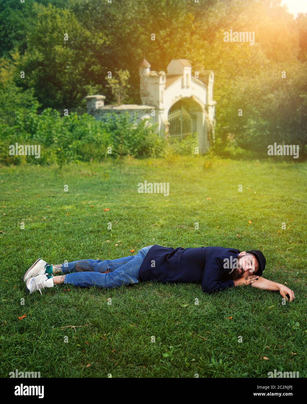 Homeless man sleeping on the green lawn Stock Photo