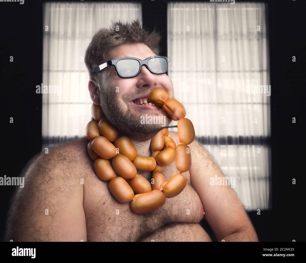 Happy bearded man eating sausages from his neck Stock Photo Alamy