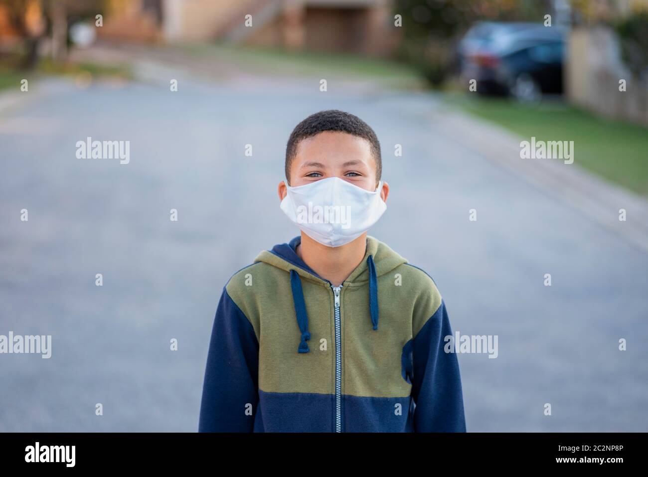 Portrait of young boy with mask on standing in road with blurred