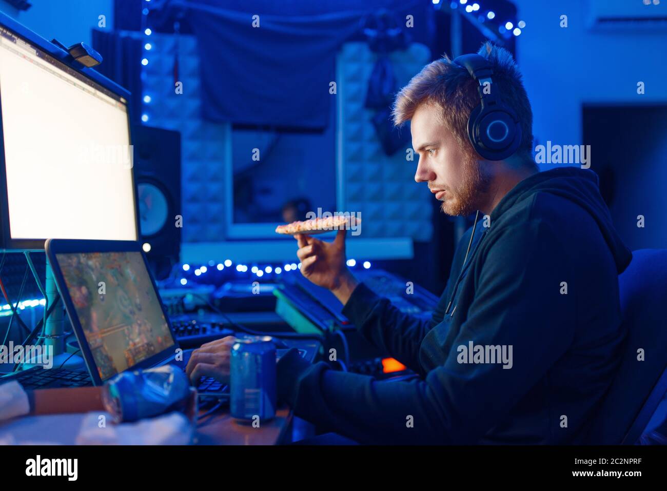 Male gamer drinking an energy drink at his workplace with laptop and