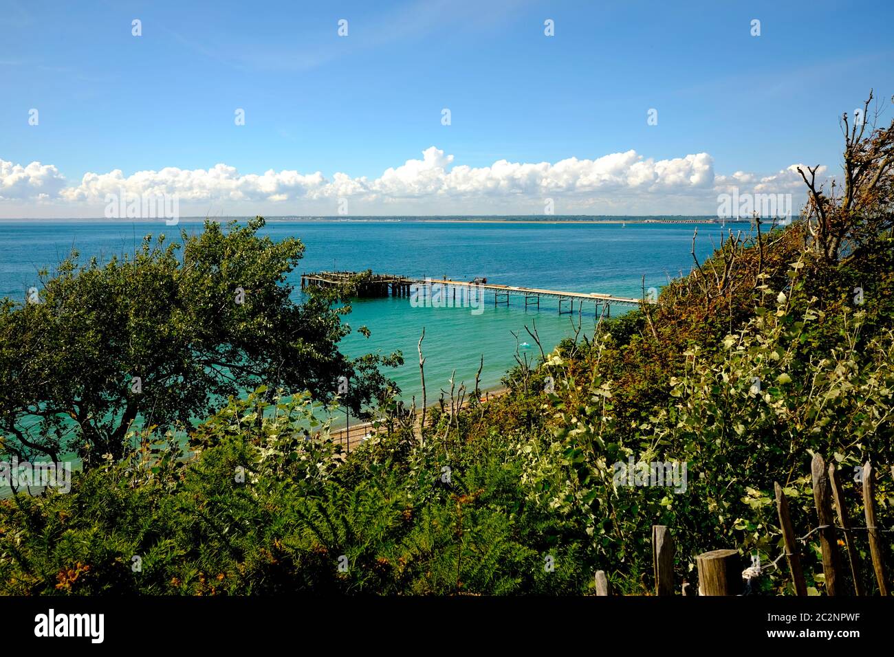 View of the Solent from the Turf Walk at Totland Bay Isle of Wight Totland Pier blue sky sea fluffy white clouds on horizon cliff top. Stock Photo