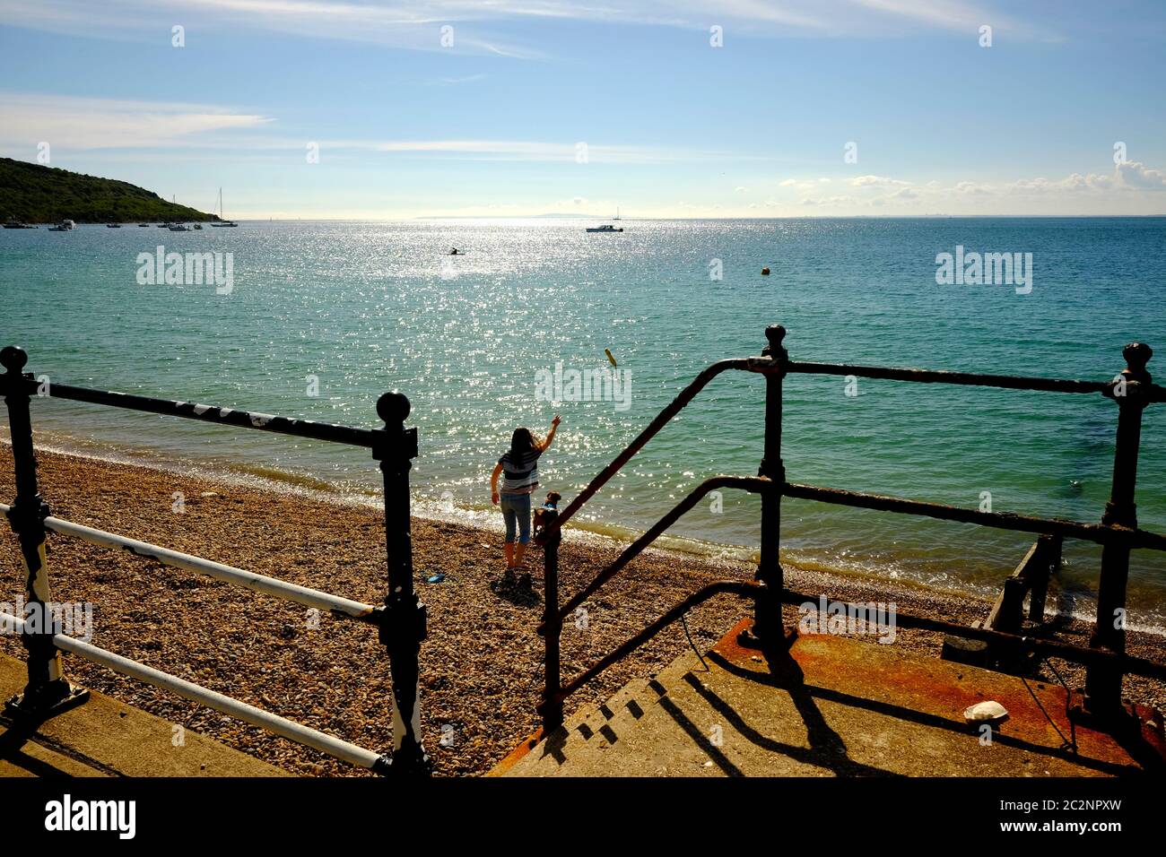 Throwing a stick for the dog into the sea from the beach shoreline on Totland Bay Isle of Wight Stock Photo